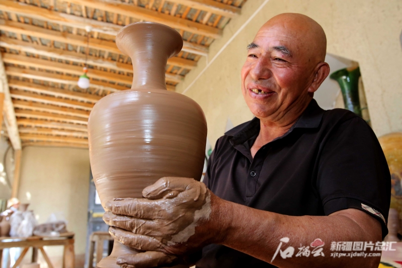 6月19日，英吉沙縣芒辛鎮(zhèn)恰克日庫(kù)依村土陶非遺傳承人阿卜杜熱合曼·麥麥提敏在欣賞剛制作的土陶作品。石榴云/新疆日?qǐng)?bào)記者 蔡增樂(lè) 攝