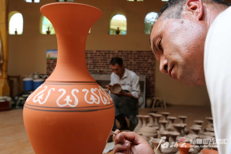 6月19日，恰克日庫(kù)依村土陶制作藝人伊馬木·艾力在土陶罐上畫(huà)畫(huà)。石榴云/新疆日?qǐng)?bào)記者 蔡增樂(lè) 攝